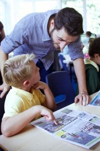 A teacher talks with a pupil about an article from First News